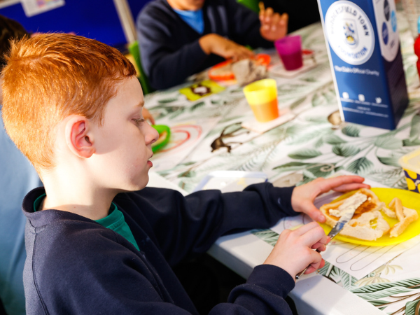 Male child buttering his toast during breakfast club